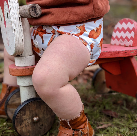 toddler wearing little lovebum fox cloth nappy on a tricycle